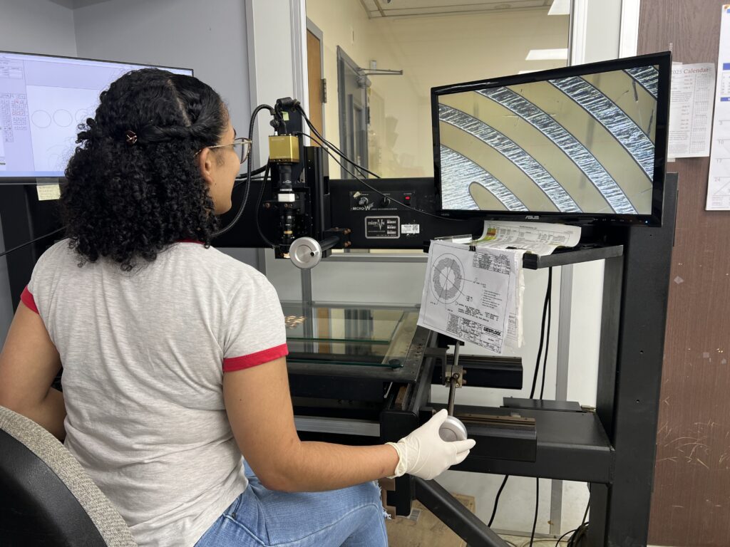 Person using a digital microscope workstation to inspect a component displayed on a monitor.